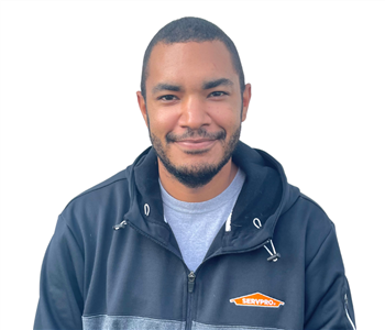 Man with dark hair wearing black SERVPRO jacket against white backdrop